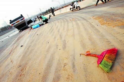 被撞的環衛工躺在地上，身上蓋著藍色布塊，現場除散落的汽車碎片外，還留有被撞斷的掃帚。