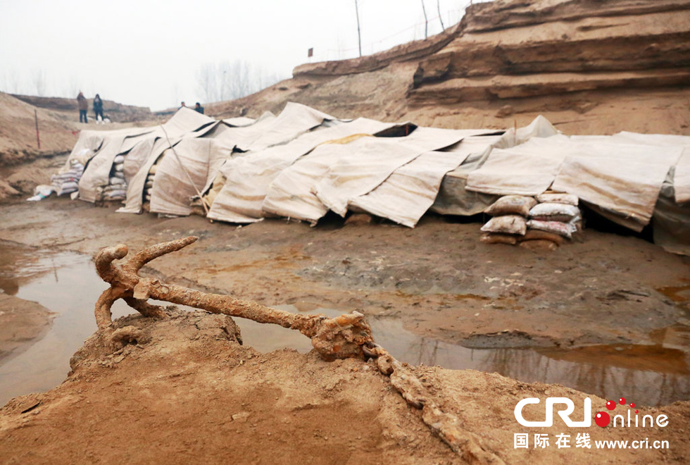 2014年1月6日，河南洛陽古沉船發(fā)掘現(xiàn)場，古沉船鐵錨從見天日，靜靜地躺在古船旁。