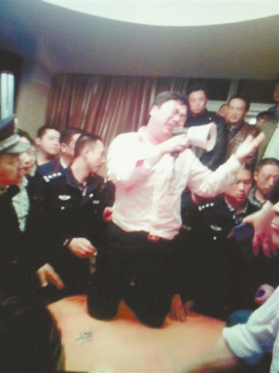 　4月19日，泰州市濱江工業園區管委會招待中心，一男子跪在酒桌上喊話求饒。李根 攝