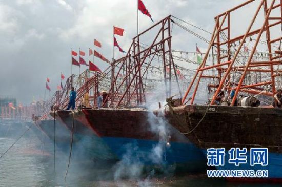 2013年8月1日 南海開漁日 臨高迎新港 8月1日，海南省臨高縣漁民在船上鳴放鞭炮慶祝武蓮港開港。