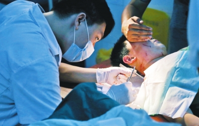 孩子身上有7道傷痕，其中兩道需要縫合，其他的均為擦傷，醫生正對他施治。