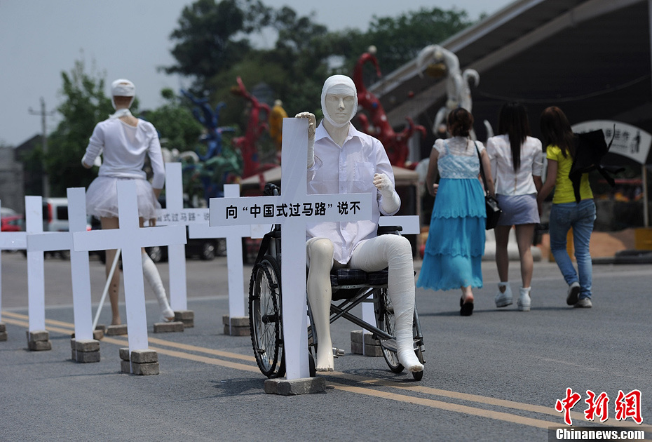 4月16日,重慶市洋人街上擺放著兩個受了傷的塑料人像“模特”,旁邊十字架上寫著向“中國式過馬路”說不 4月16日,重慶市洋人街上擺放著兩個受了傷的塑料人像“模特”,旁邊十字架上寫著向“中國式過馬路”說不