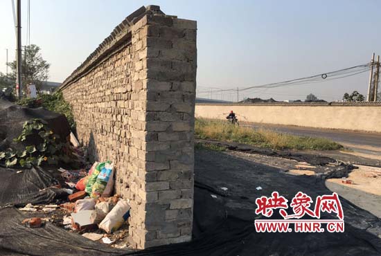 一墻之隔，一邊是道路，一邊是垃圾和荒草，市民質疑其為遮羞墻。