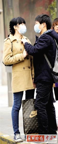 公交站臺上,一對年輕人戴著口罩,系緊衣領。 公交站臺上,一對年輕人戴著口罩,系緊衣領。